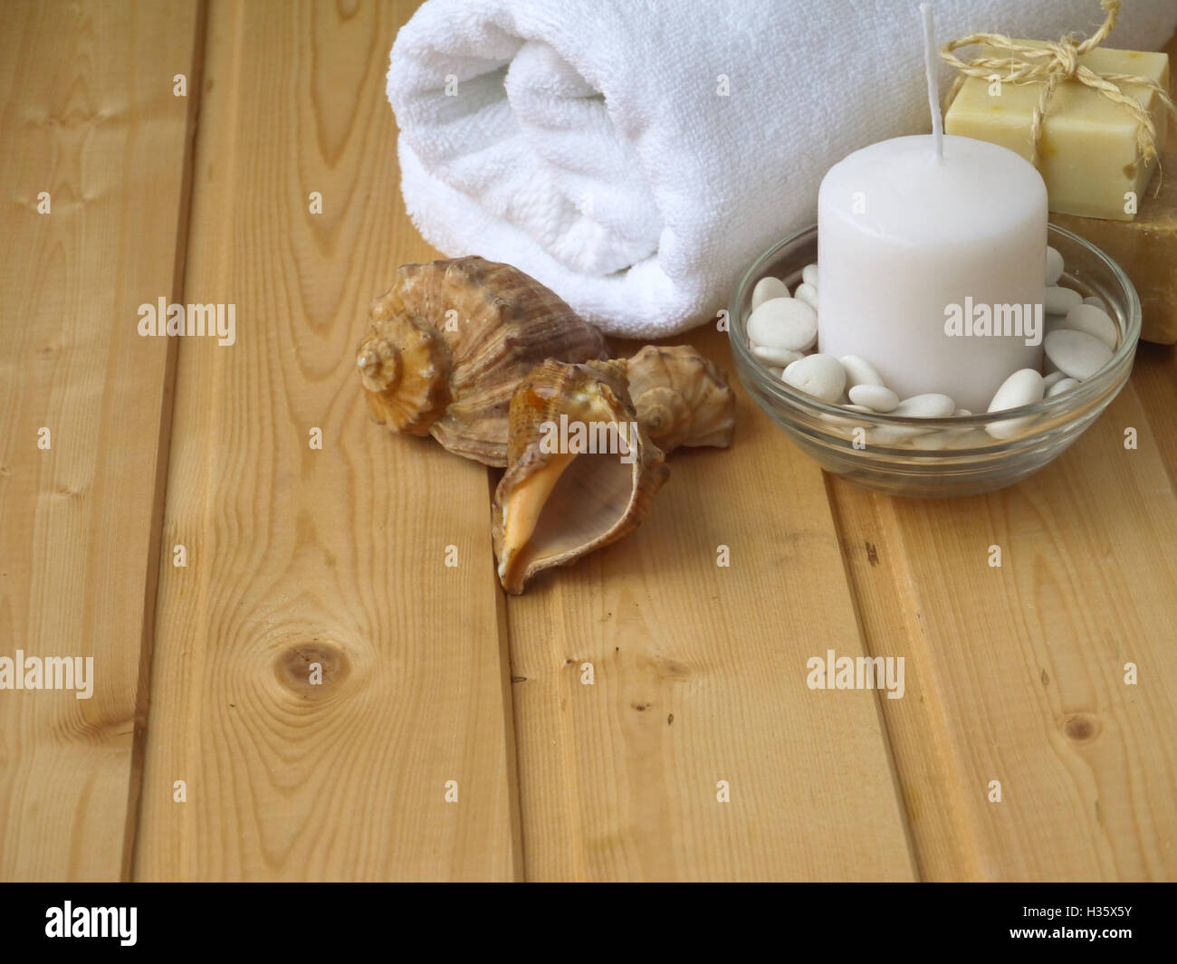 Handtuch, Seife, Kerzen und Muscheln auf dem hölzernen Hintergrund Stockfoto