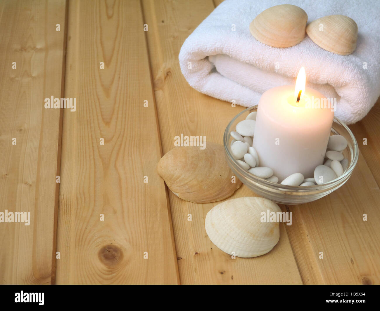 Handtuch, Muscheln und brennende Kerze auf dem hölzernen Hintergrund Stockfoto