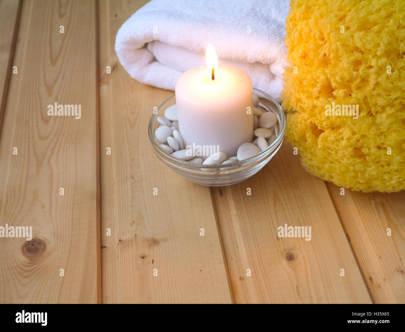 Handtuch, brennende Kerze und Schwamm auf dem hölzernen Hintergrund Stockfoto