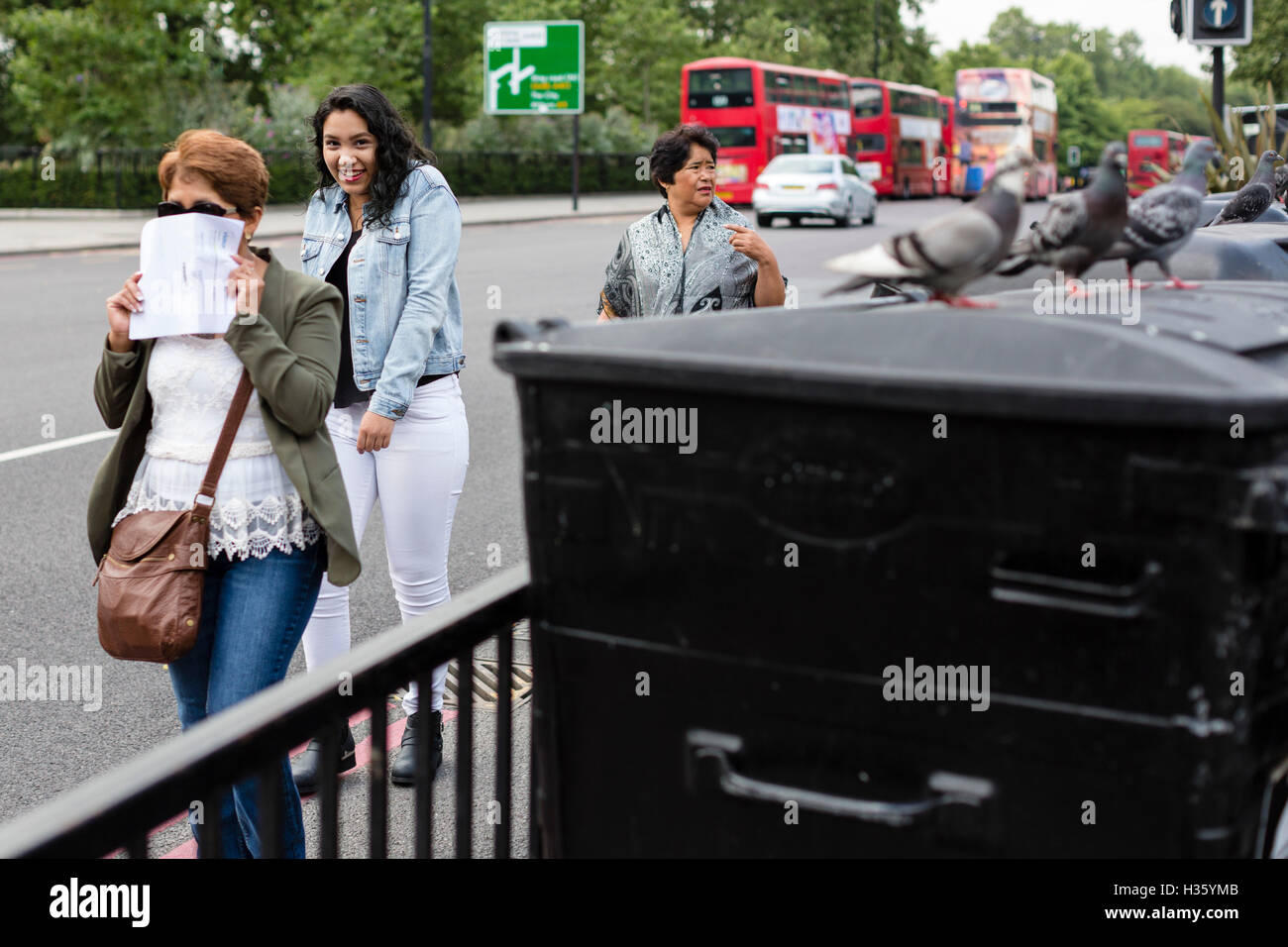 Frauen gehen vorbei an Mülltonnen und Tauben, Ecke Marble Arch, London. Stockfoto