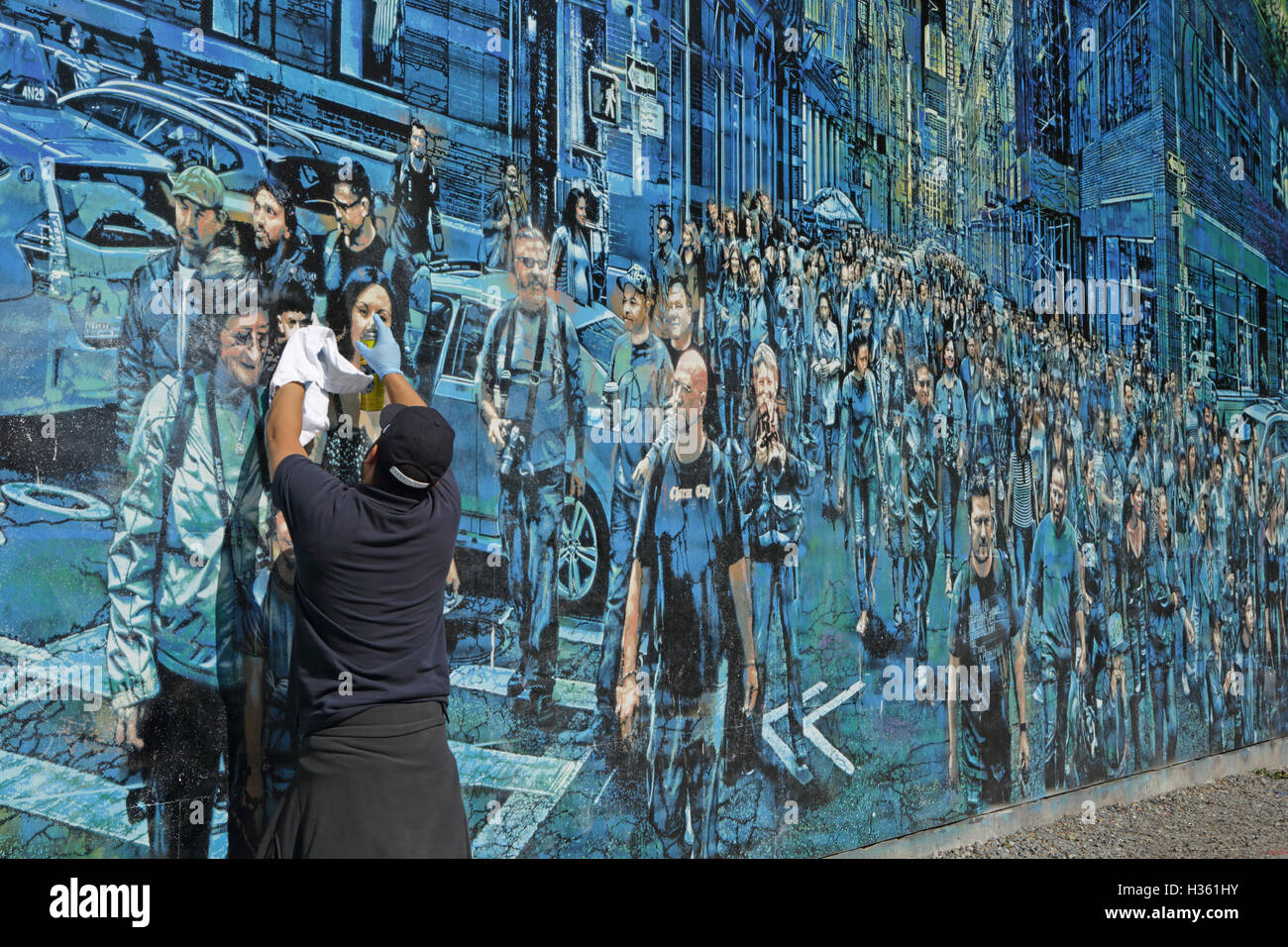 Ein Wärter reinigt Graffiti aus ein großes Wandgemälde von Logan Hicks an der Bowery Wandbild Wand, Houston Street Stockfoto