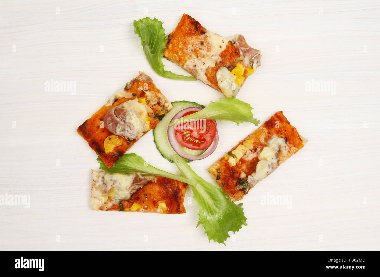 Pizzastücke und Salat garnieren, auf weiß lackiertem Holz Stockfoto