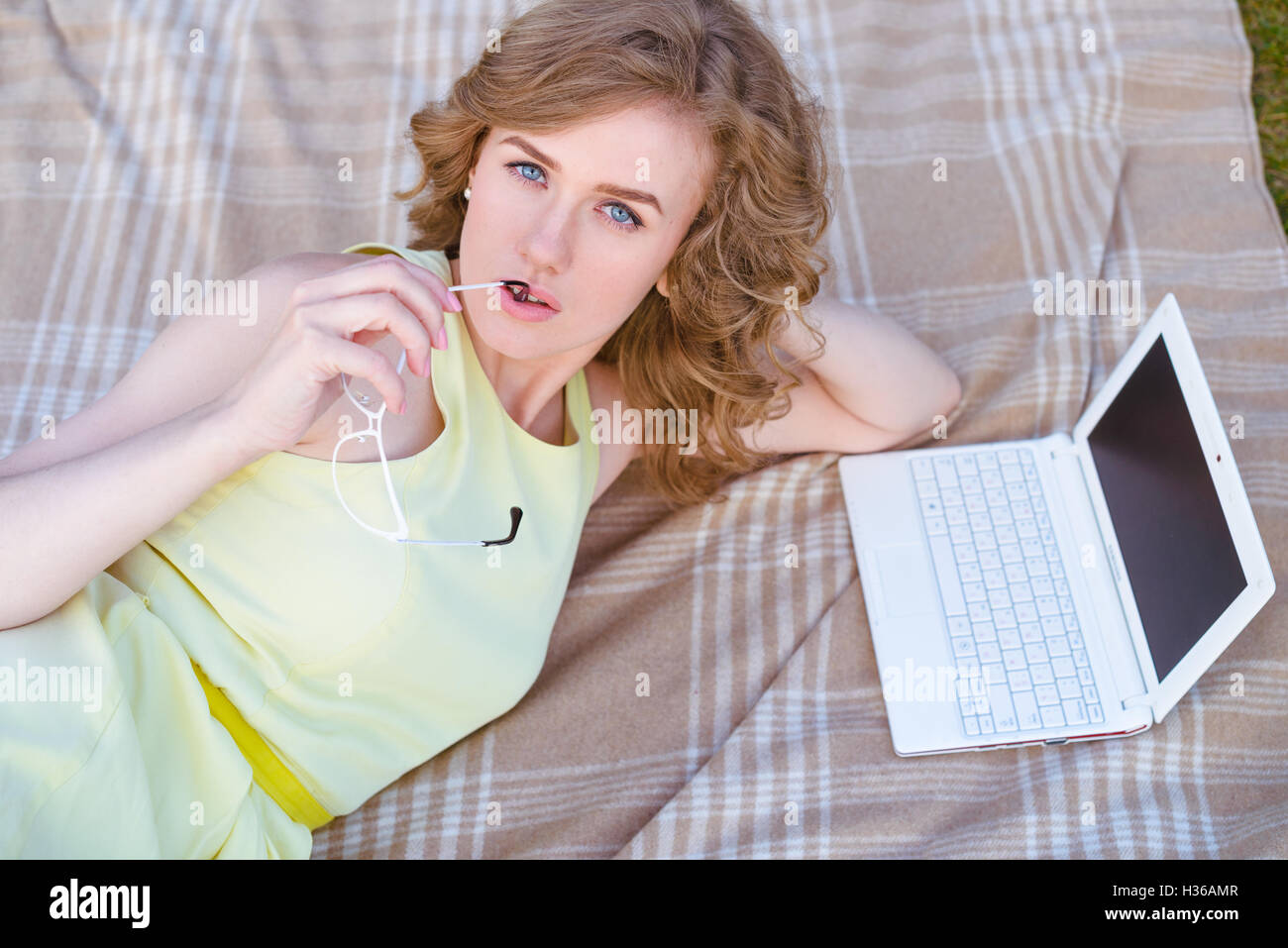 junge Frau auf Decke mit Notebook im freien Stockfoto