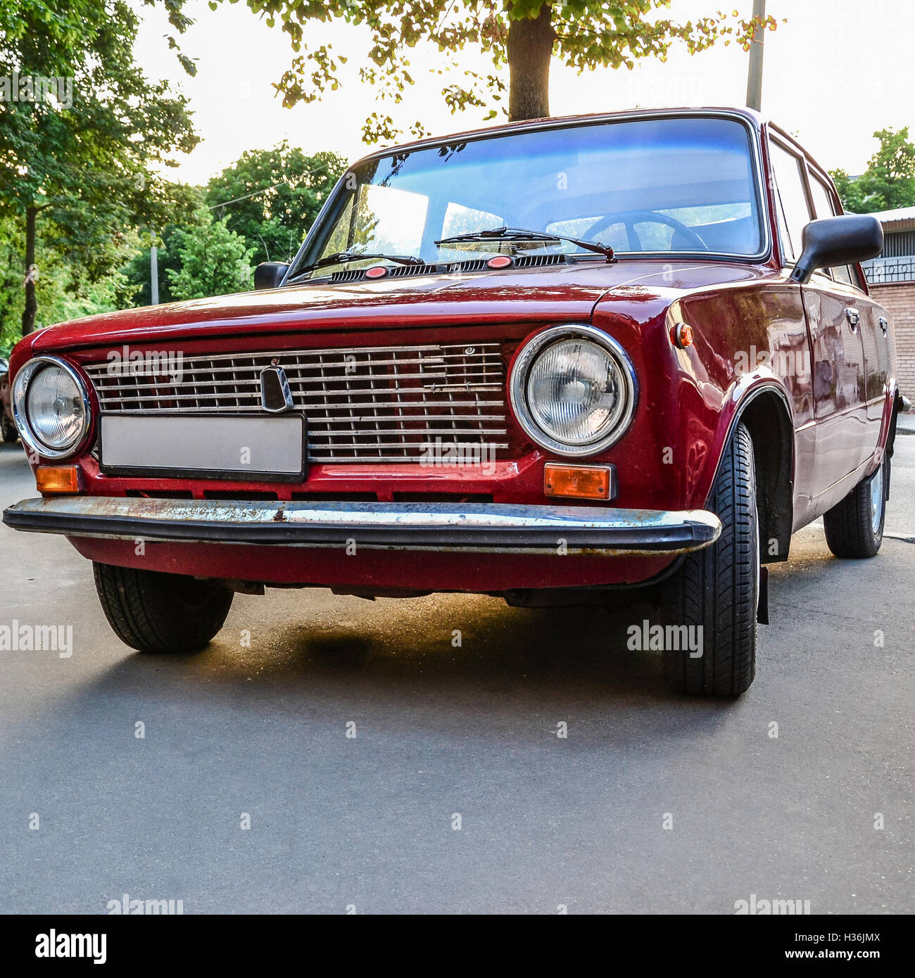 Rote Vintage Retro-Auto unter Baum bei Sonnenuntergang Stockfoto
