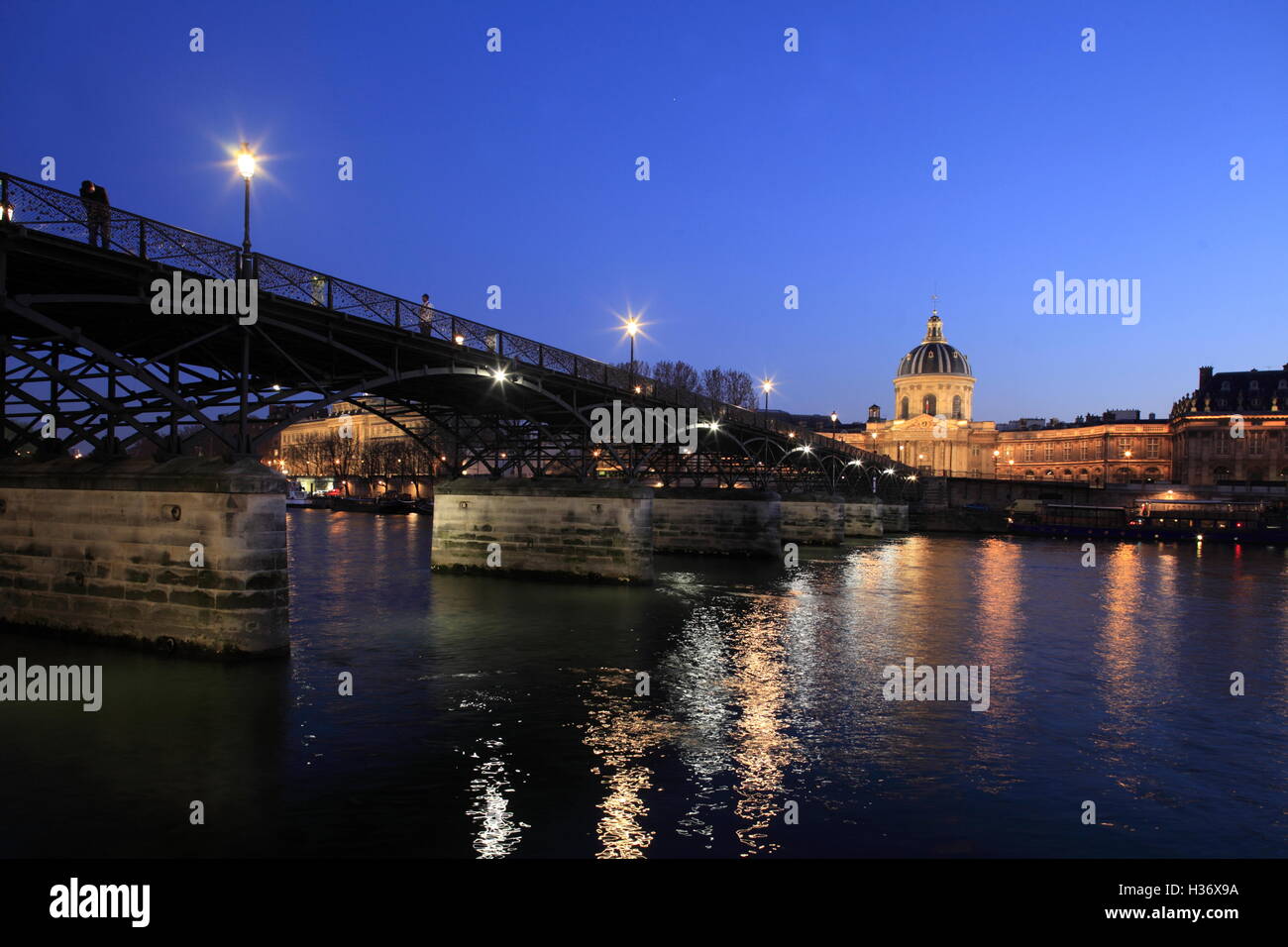 Nachtansicht der Pont des Arts (Kunst-Brücke) über Fluss Seine mit L'Academie Francaise (Académie) im Hintergrund. Paris, Frankreich Stockfoto