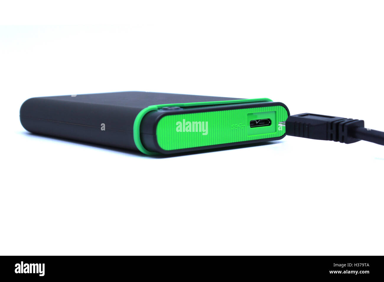 Grüne externe Festplatte und schwarzes Kabel Stockfoto