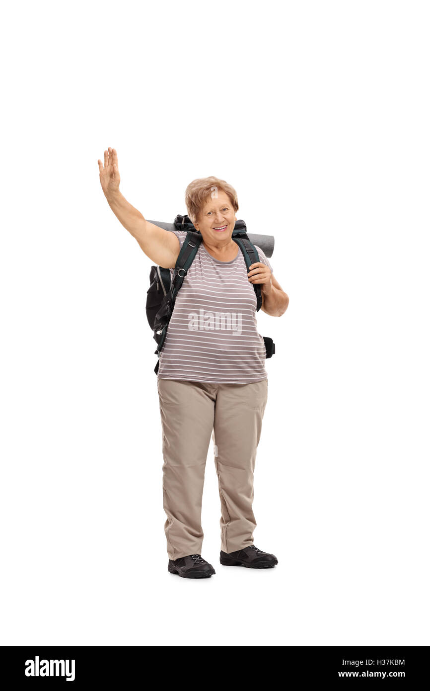 In voller Länge Portrait von einem älteren weiblichen Wanderer winken in die Kamera, die isoliert auf weißem Hintergrund Stockfoto