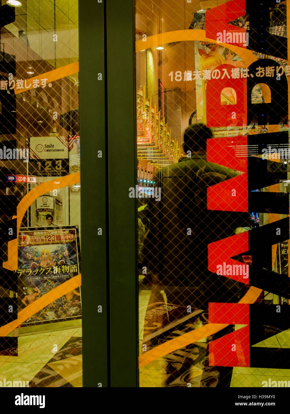 Mann von hinten durch die Glas Tür Eingang von Pachinko Salon, Namba, Osaka, Japan. Stockfoto