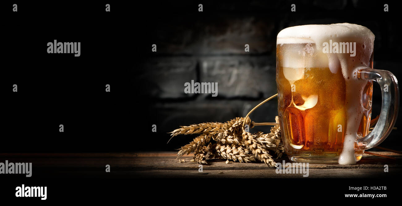 Bier im Becher auf Holztisch in der Nähe von Mauer Stockfoto