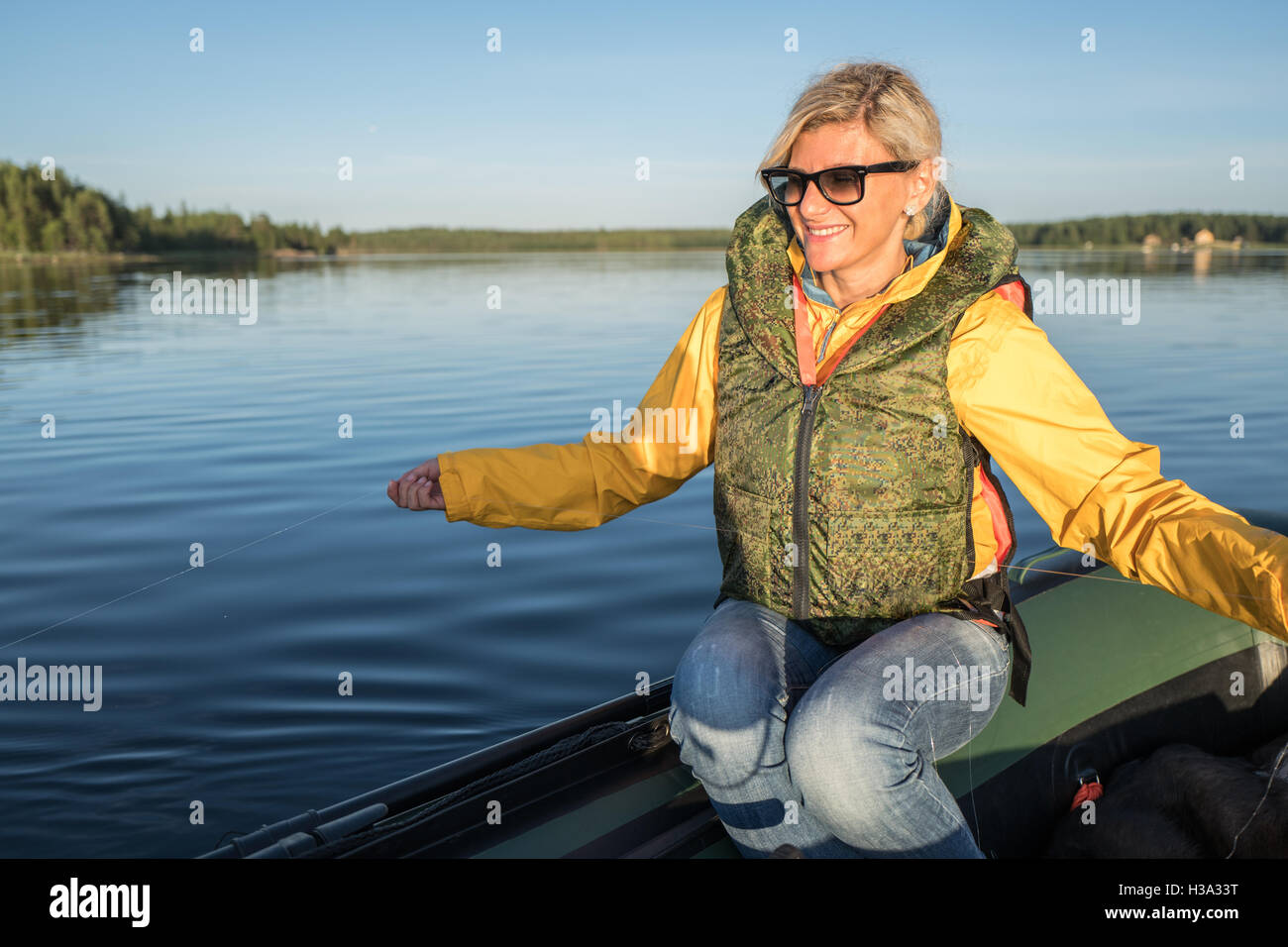 Blonde Mädchen sitzt auf dem Boot mit Angelschnur in Ihren Händen Stockfoto