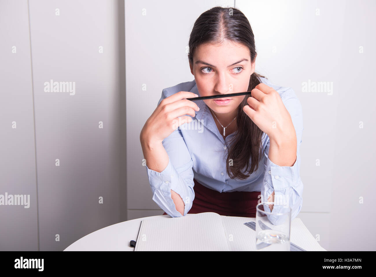 junge Frau mit Bleistift unter ihrer Nase denkt Stockfoto