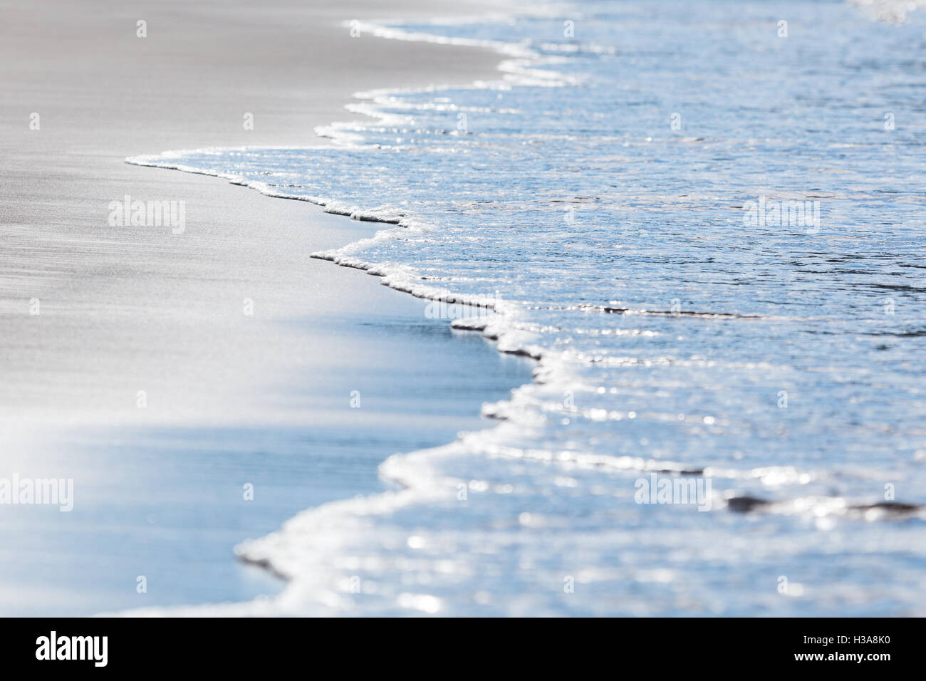 Wellen treffen schwarzen vulkanischen Sand der Playa Matapalo an der Küste von Guanacaste. Stockfoto