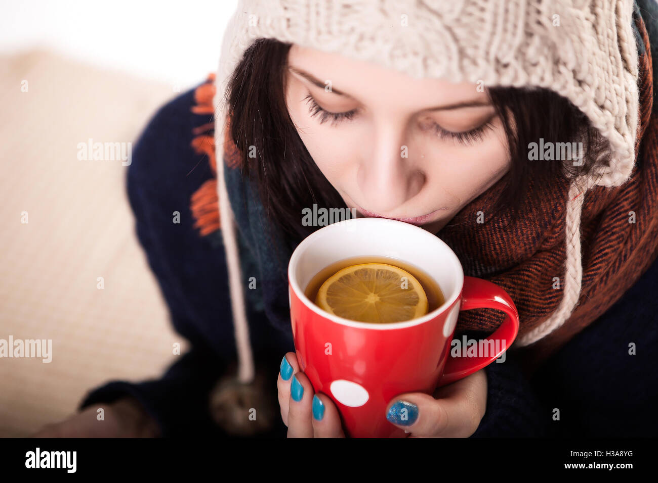 Frau eine große Tasse frisch gebrühtem Tee genießen, wie sie auf dem Sofa im Wohnzimmer entspannt Stockfoto