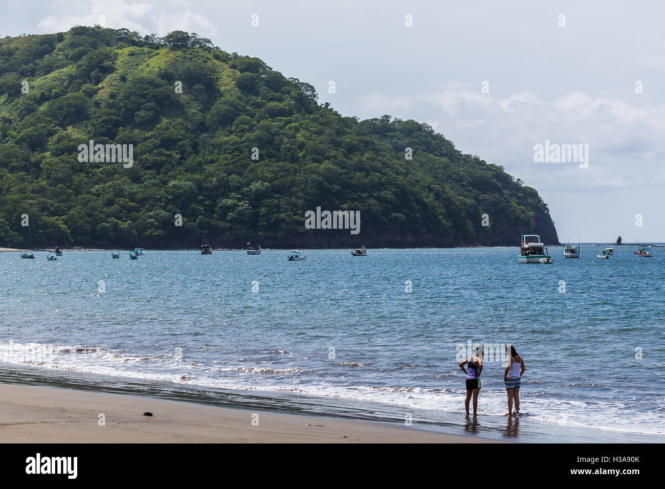 Lokale Leute reden auf Coco Beach als private Boote besetzen den Hintergrund. Stockfoto