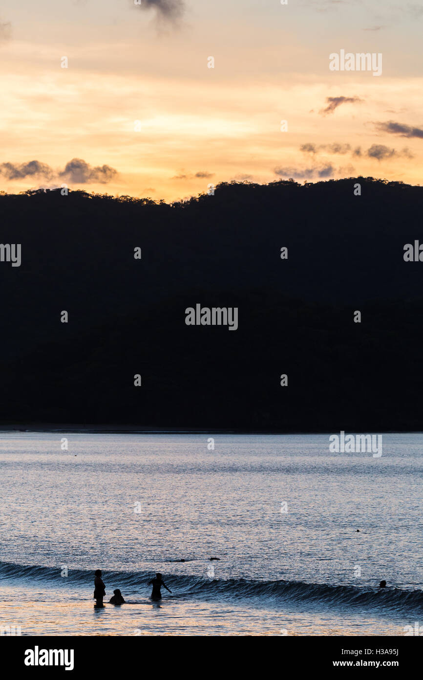 Ticos (lokale Wort verwendet, um native Costaricaner beschreiben) spielen im Wasser bei Sonnenuntergang an der Küste von Guanacaste. Stockfoto
