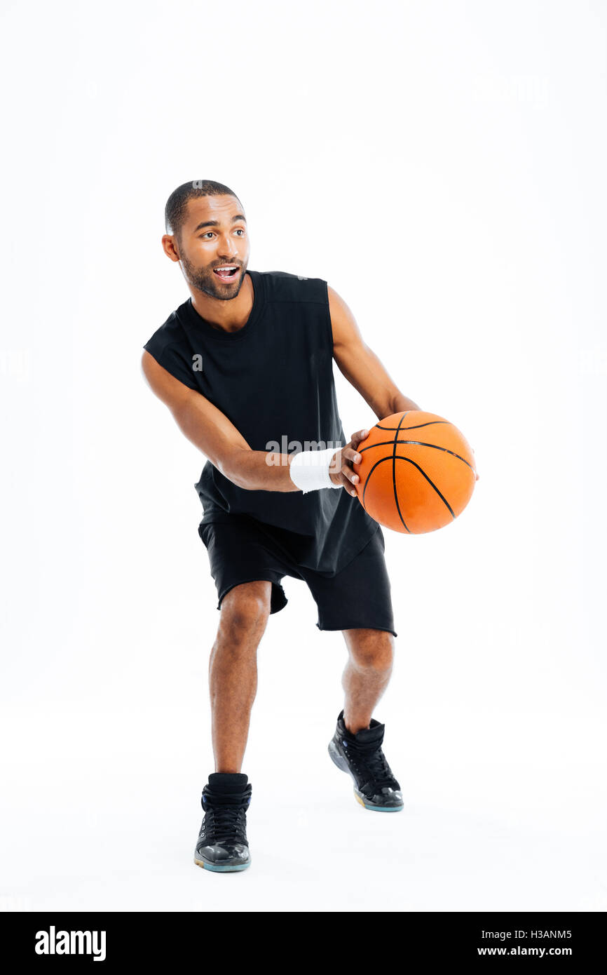 Voller Länge Porträt eines lächelnden jungen Sportler spielen Basketball auf einem grauen Hintergrund isoliert Stockfoto