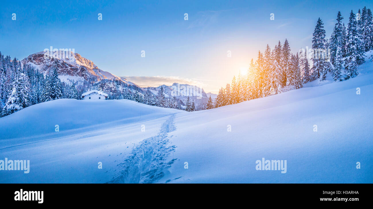 Panoramablick über schöne Winter Wunderland Berglandschaft mit traditionellen Berghütte Hintergrund in den Alpen im goldenen Abendlicht Stockfoto