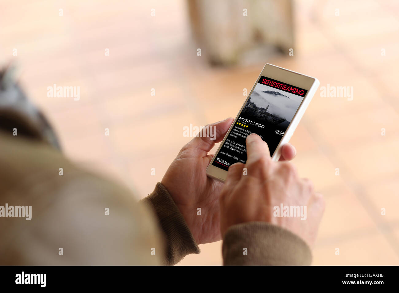 Mann durch Berühren des Bildschirms von seinem Smartphone zu Serien online sehen. Alle Bildschirm-Grafiken bestehen. Stockfoto