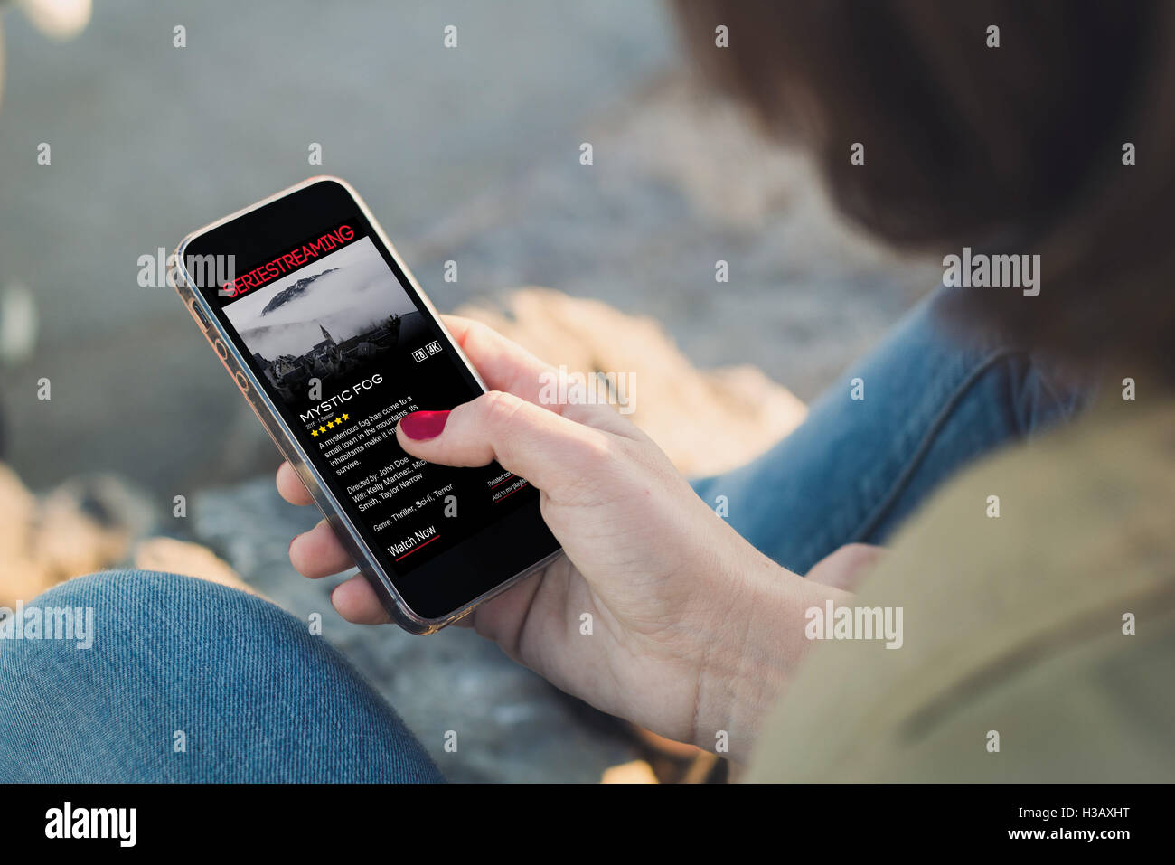 Frau hält eine Smartphone und berühren des Bildschirms zeigt Serie Streaming-Website. Alle Bildschirm-Grafiken bestehen. Stockfoto