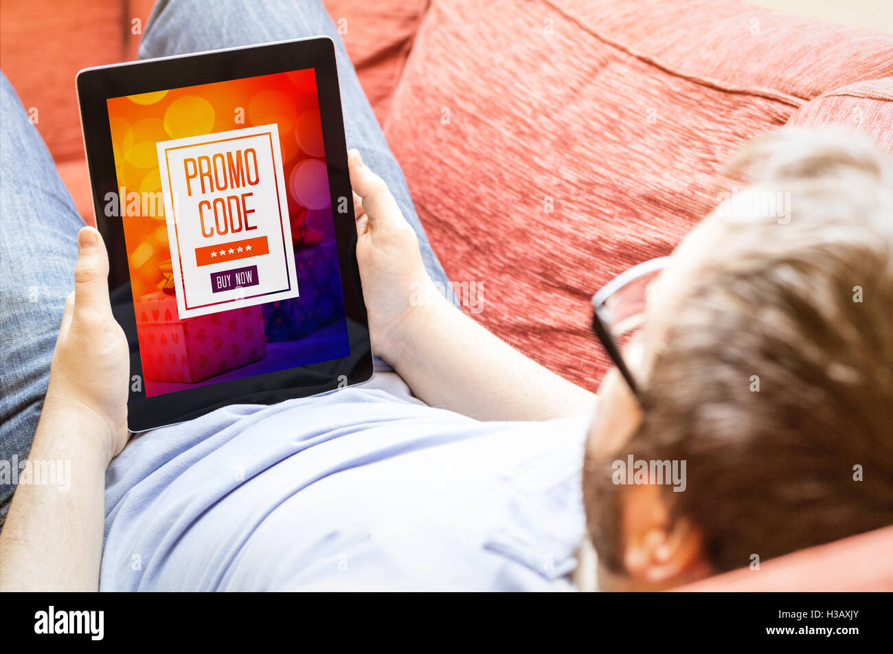 Technologie-Lifestyle-Konzept: Hipster auf dem Sofa mit Blick auf digitale Promocode Stockfoto