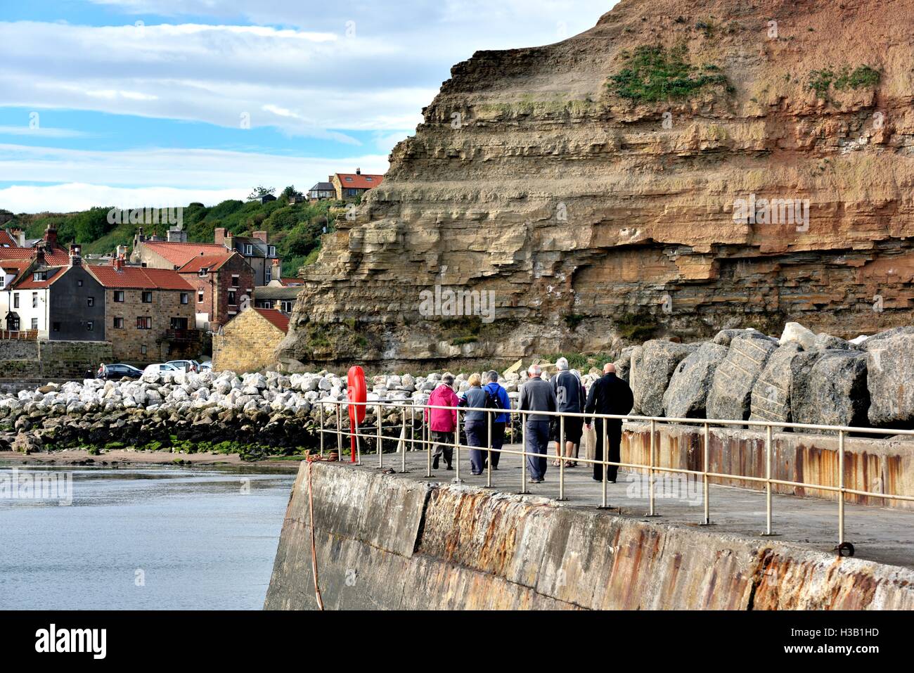 Menschen spazieren entlang des Hafens Wand in Staithes North Yorkshire England UK Stockfoto