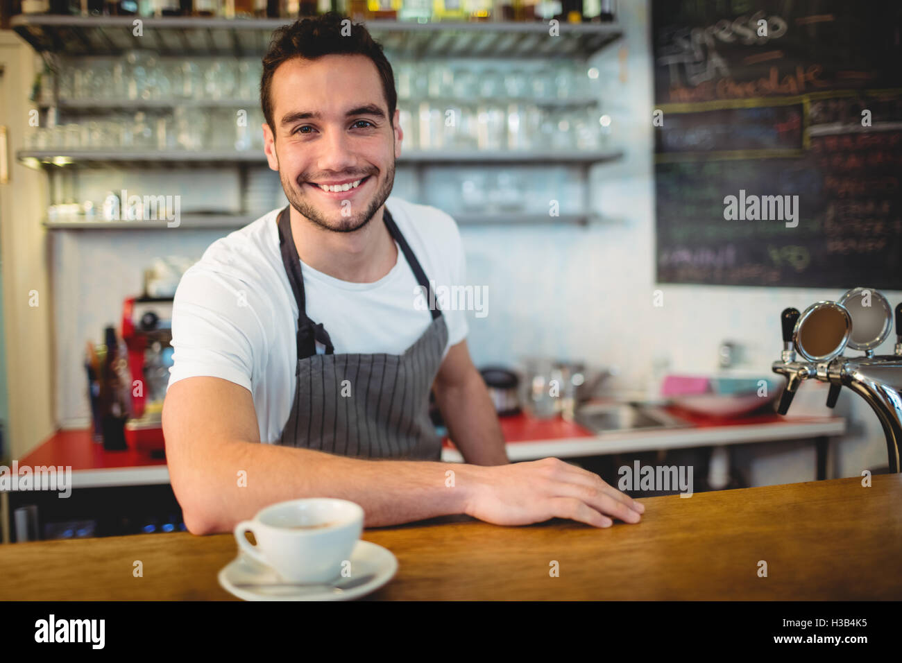 Porträt von zuversichtlich Kellner mit Kaffee am Schalter Stockfoto