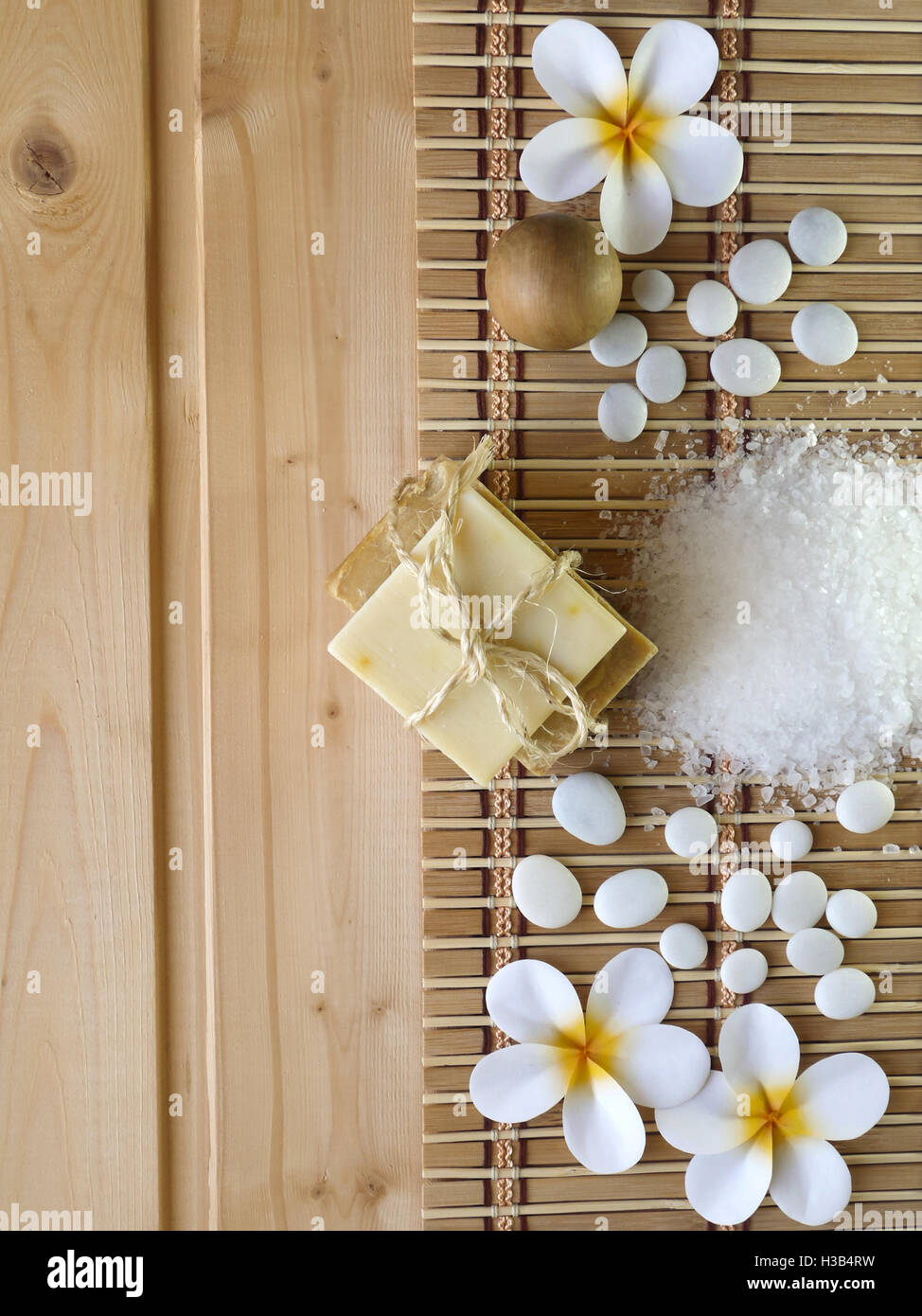 Seife, Holzkugel, Steinen und Tiare Blüten auf dem hölzernen Hintergrund Stockfoto