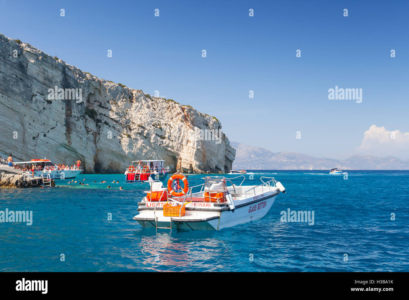 Zakynthos, Griechenland - 20. August 2016: Weiße Vergnügen Motorboot schwimmend auf Meerwasser in der Nähe von felsigen Insel Küste im Sommertag Stockfoto