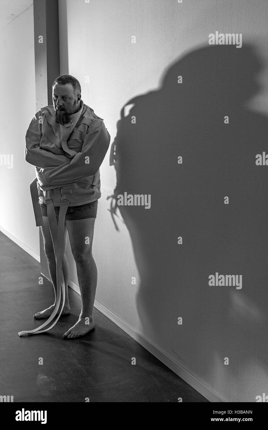 Foto von einem wahnsinnigen Mann in seinen Vierzigern, tragen eine Zwangsjacke stehend in einem Flur einer Asyl. Stockfoto