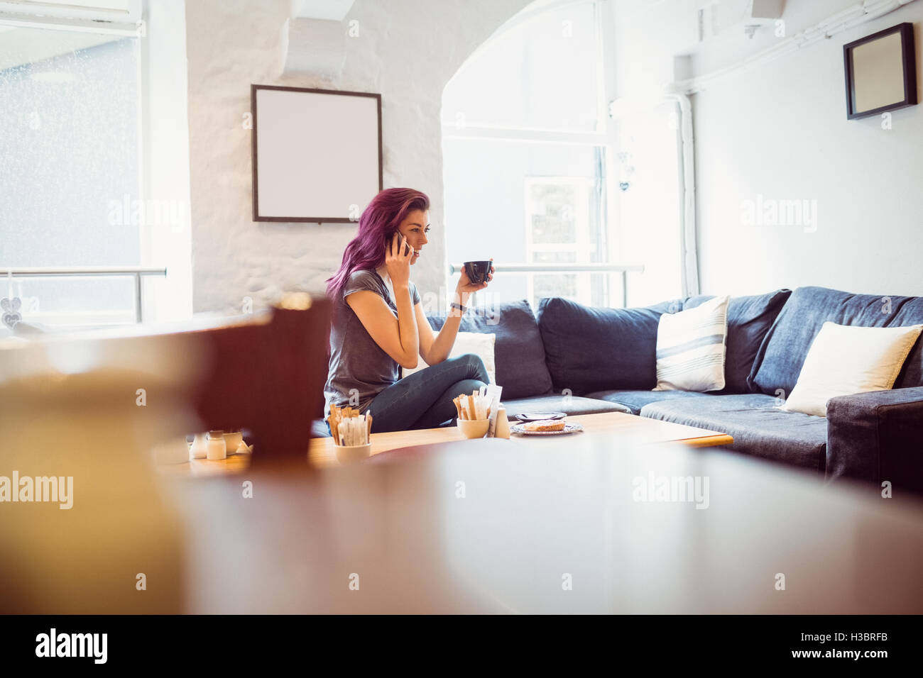 lächelnde Frau hält eine Tasse Kaffee und nehmen Sie einen Anruf Stockfoto