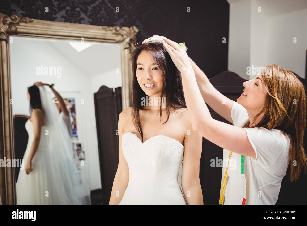 Frau versucht auf Hochzeitskleid mit Hilfe der kreativen designer Stockfoto