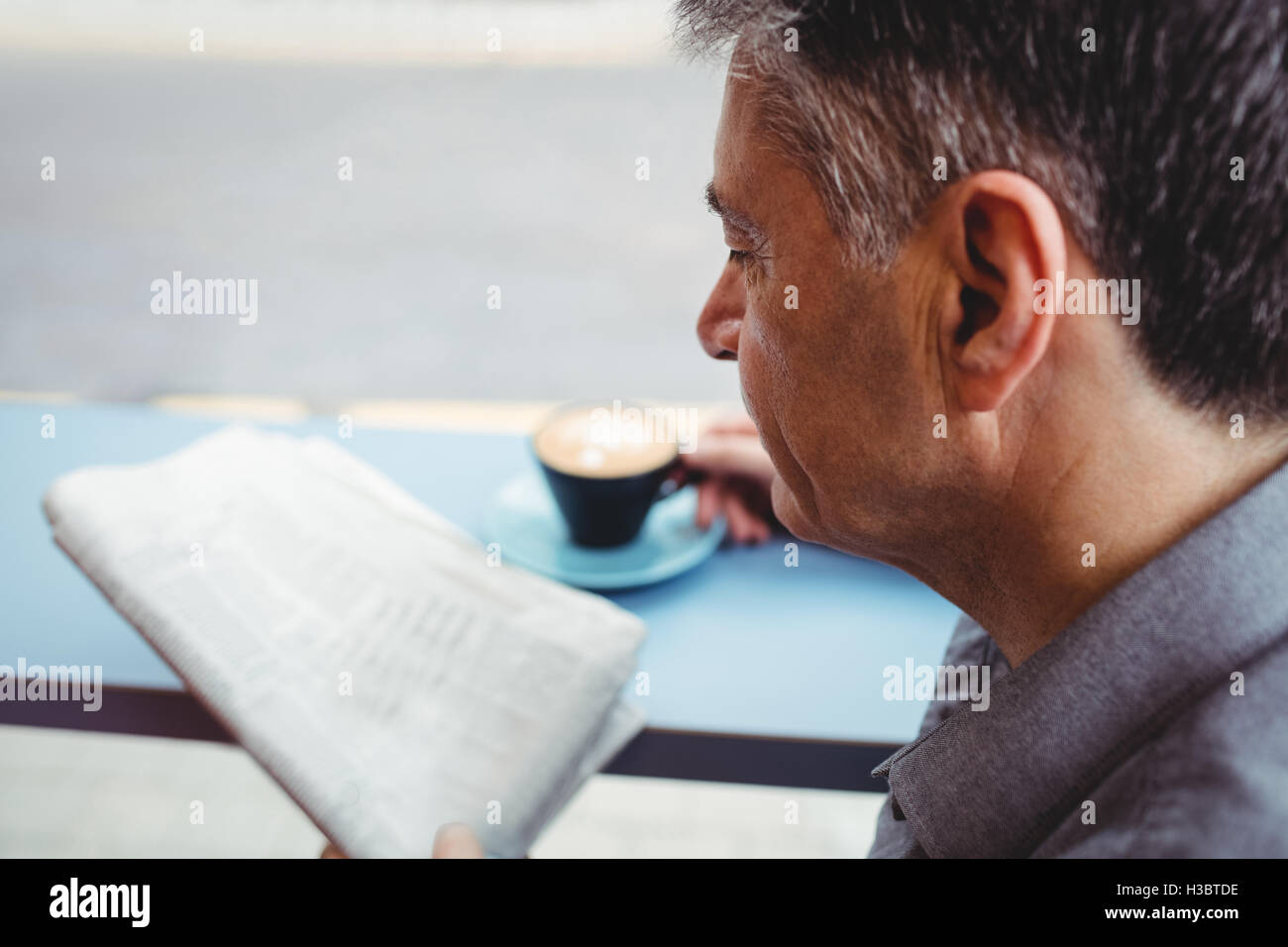 Mann liest Zeitung und Kaffee Tasse Stockfoto