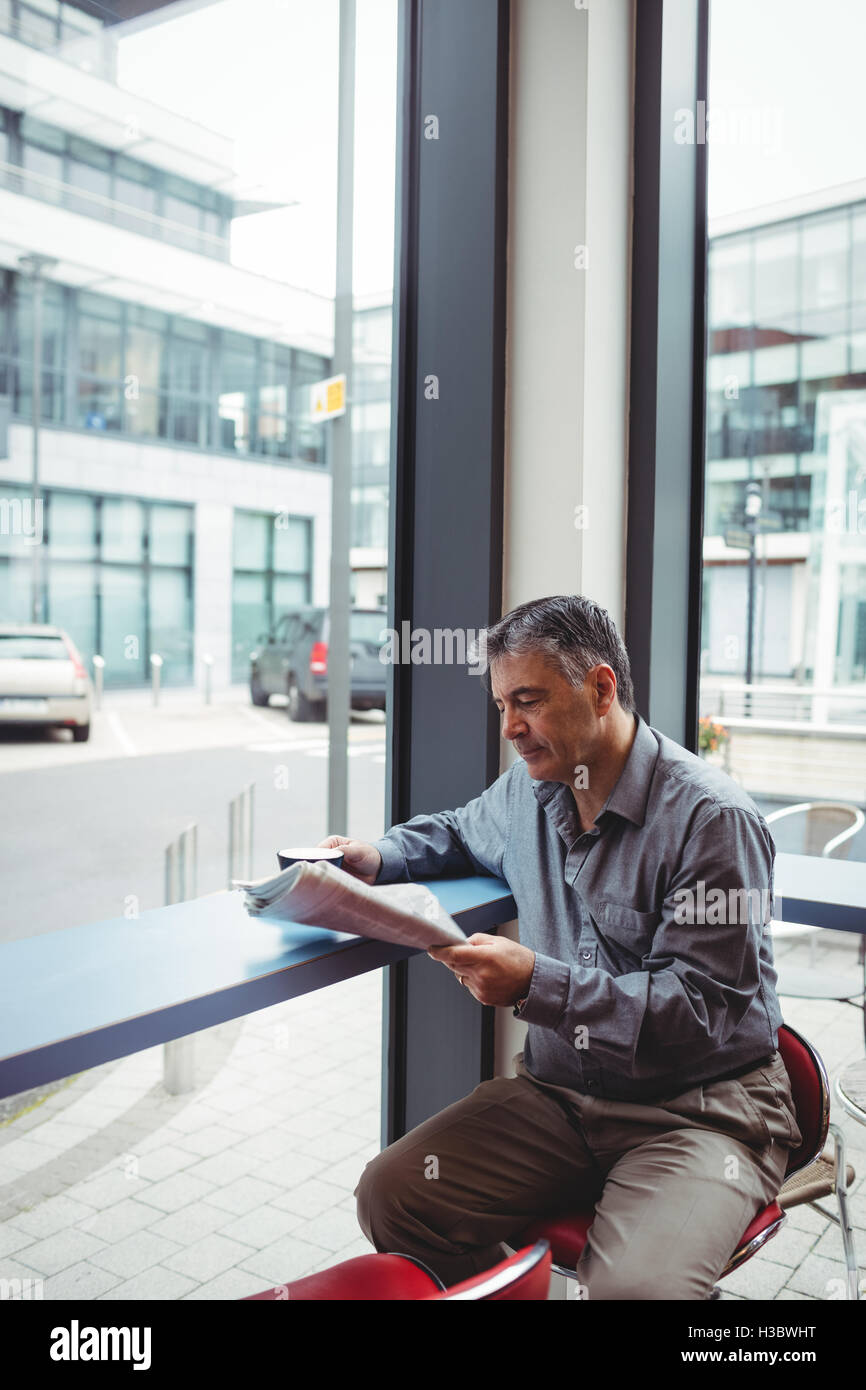 Mann liest Zeitung und Kaffee Tasse Stockfoto