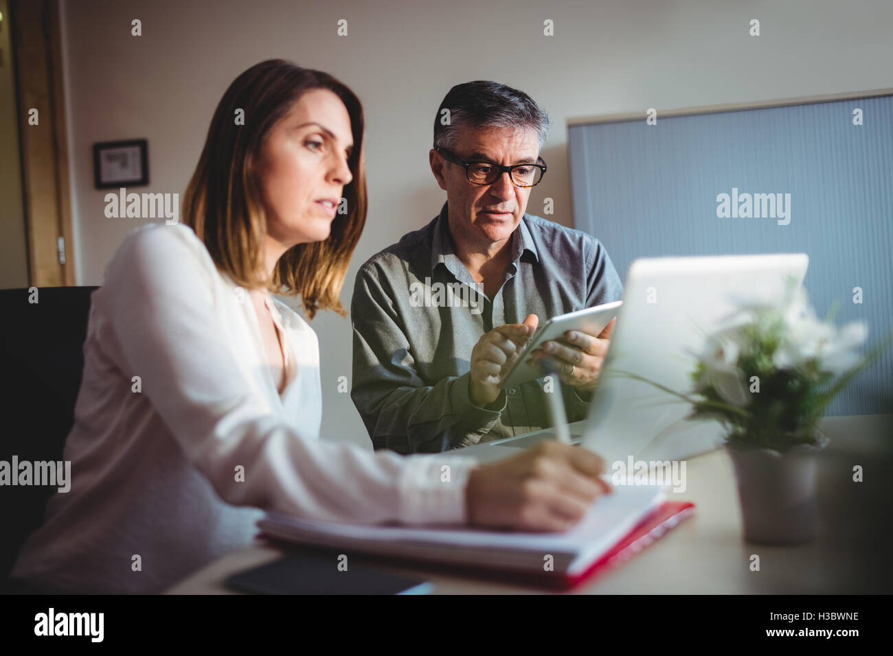 Mann und Frau diskutieren über digitale Tablet und Notebook Stockfoto