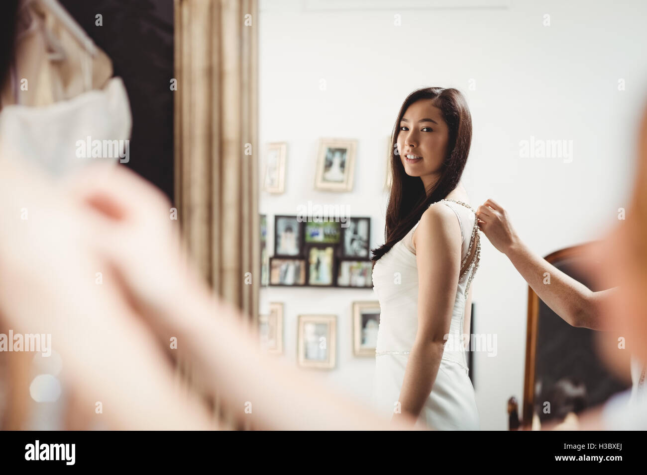 Frau versucht auf Hochzeitskleid mit Hilfe der kreativen designer Stockfoto