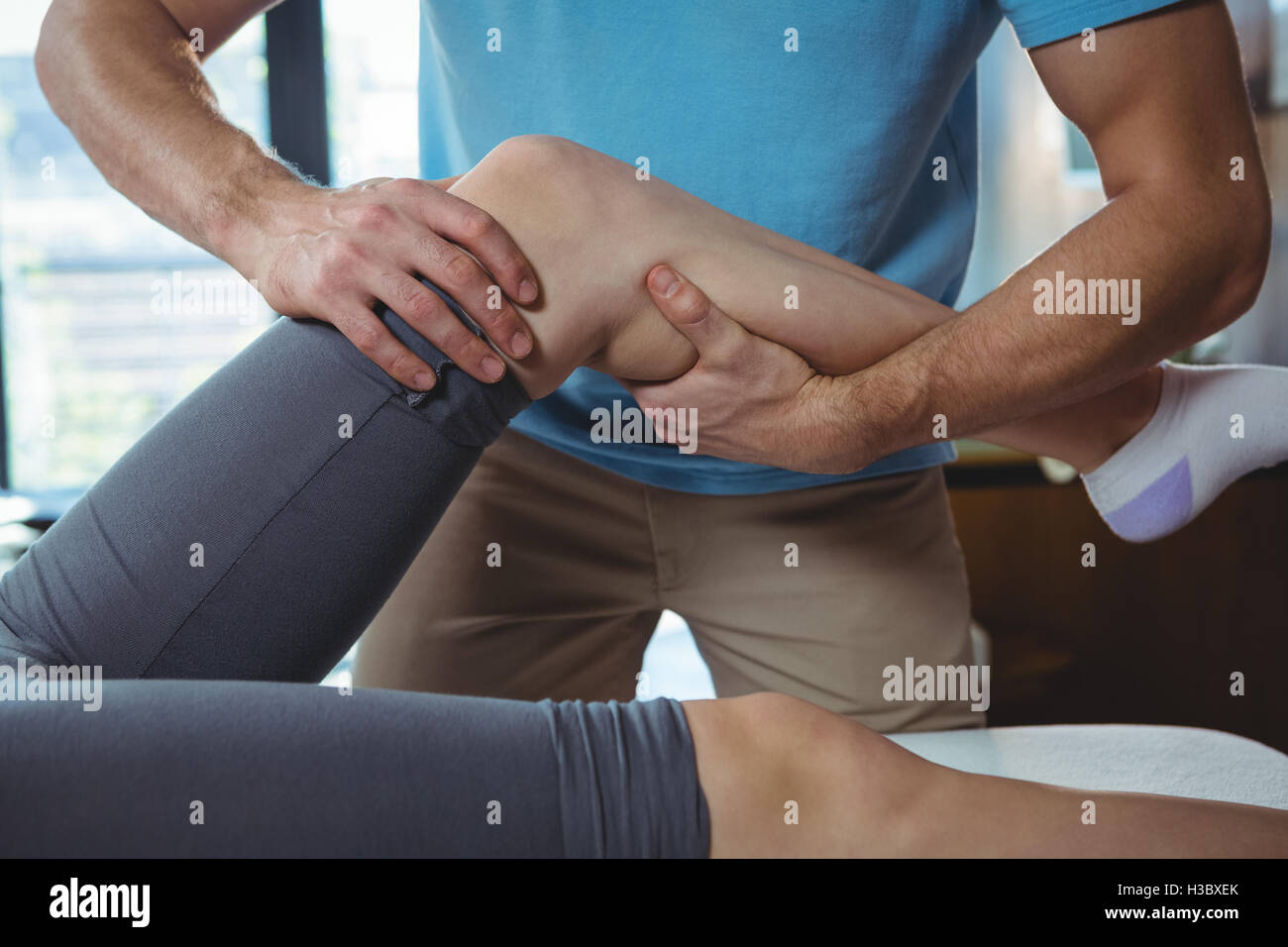 Männliche Physiotherapeuten geben Knie massieren, Patientin Stockfoto