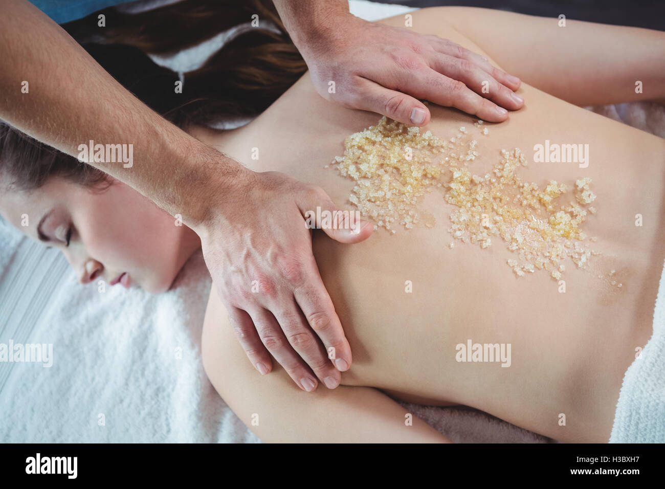 Physiotherapeuten, die Anwendung von Salz-Peeling auf der Rückseite einer Patientin Stockfoto