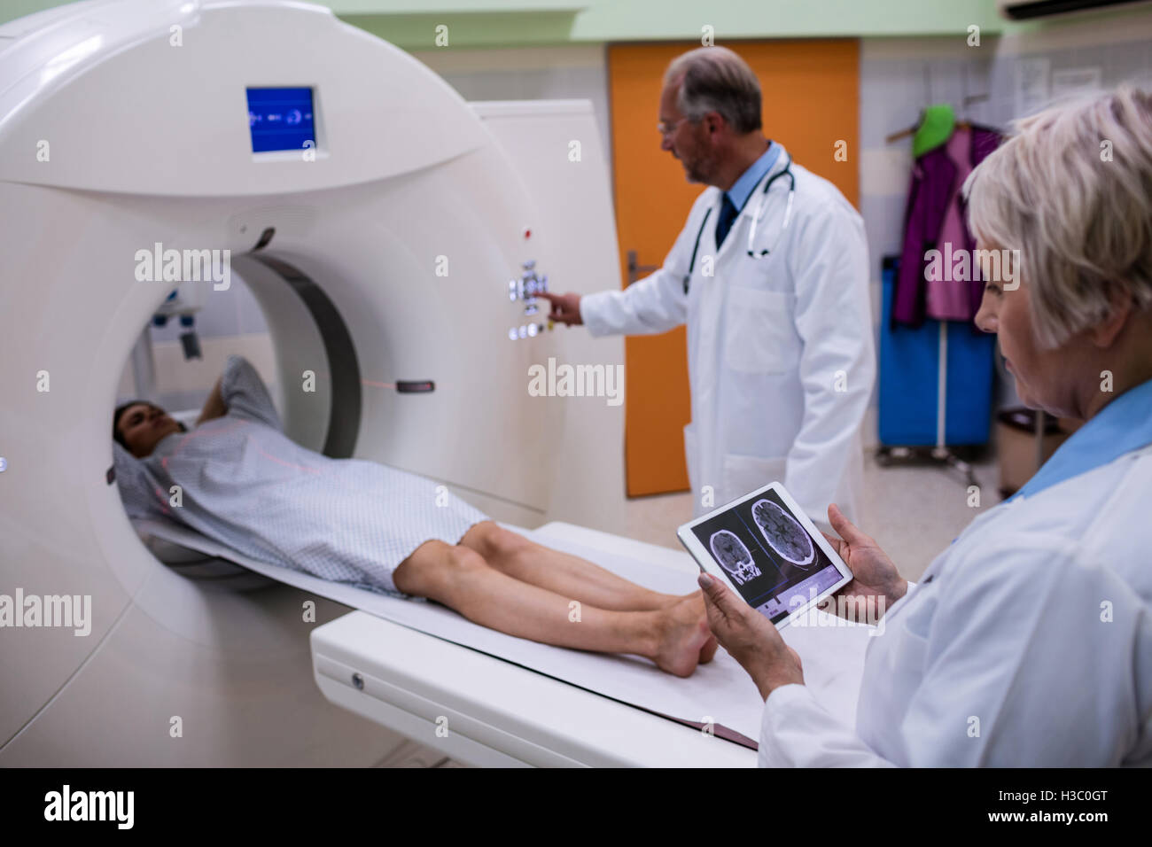 Arzt, Blick auf Gehirn-MRT-Untersuchung auf digital-Tablette und Patienten MRT-Scan-Gerät eingeben Stockfoto