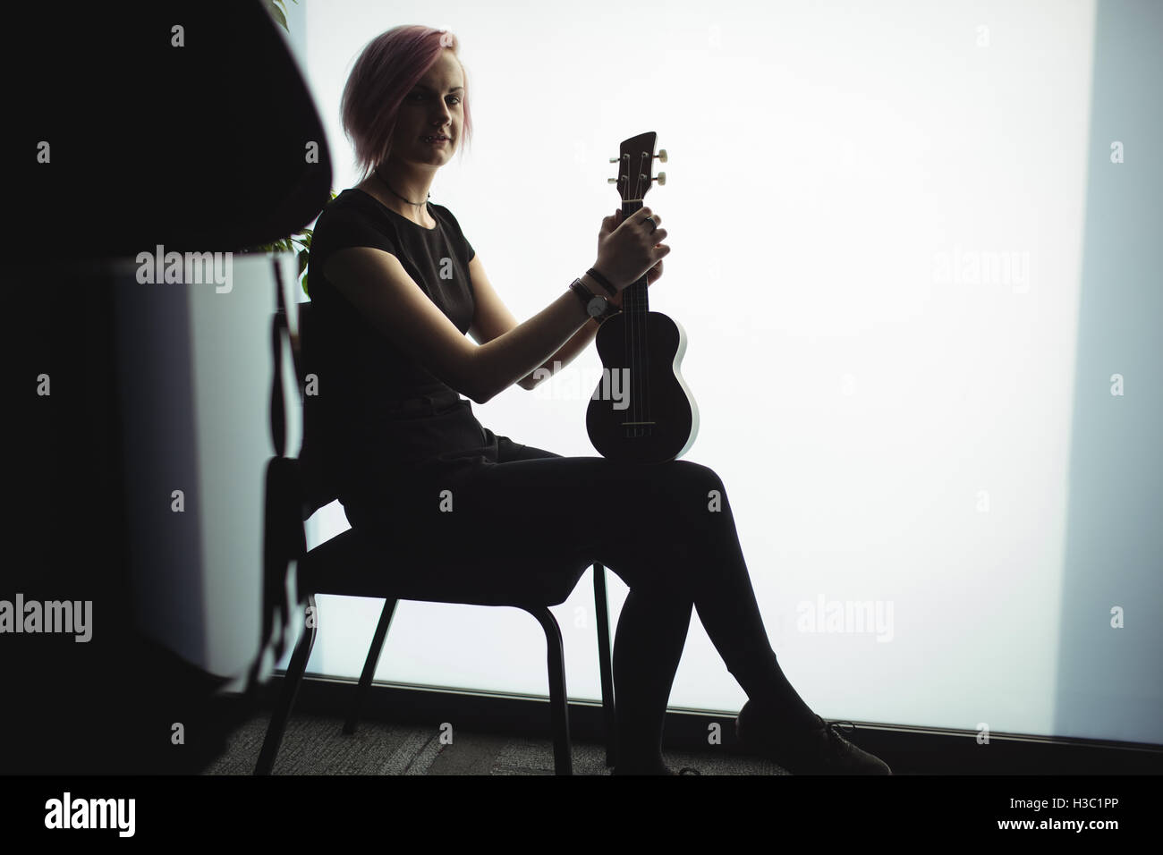 Frau sitzt mit einer Gitarre in der Musikschule Stockfoto
