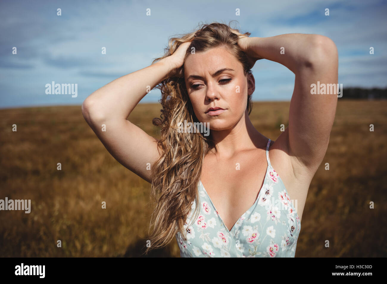 Frau mit Hand im Haar stehen im Weizenfeld Stockfoto