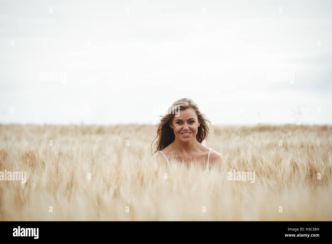 Lächelnde Frau im Weizenfeld an einem sonnigen Tag Stockfoto
