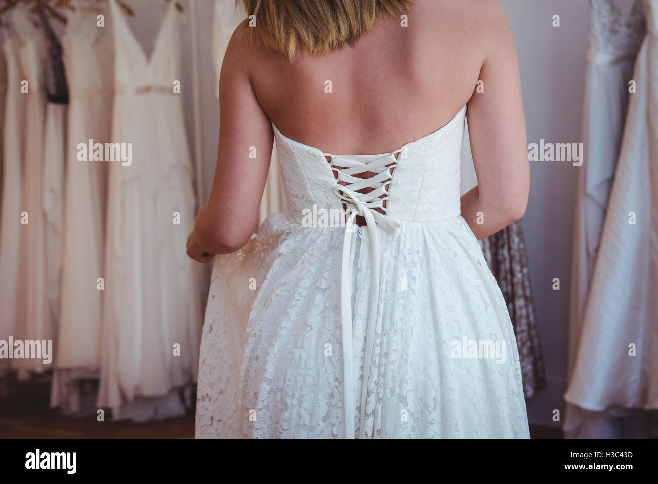 Schöne Frau, die versucht auf Hochzeitskleid in einem Geschäft Stockfoto