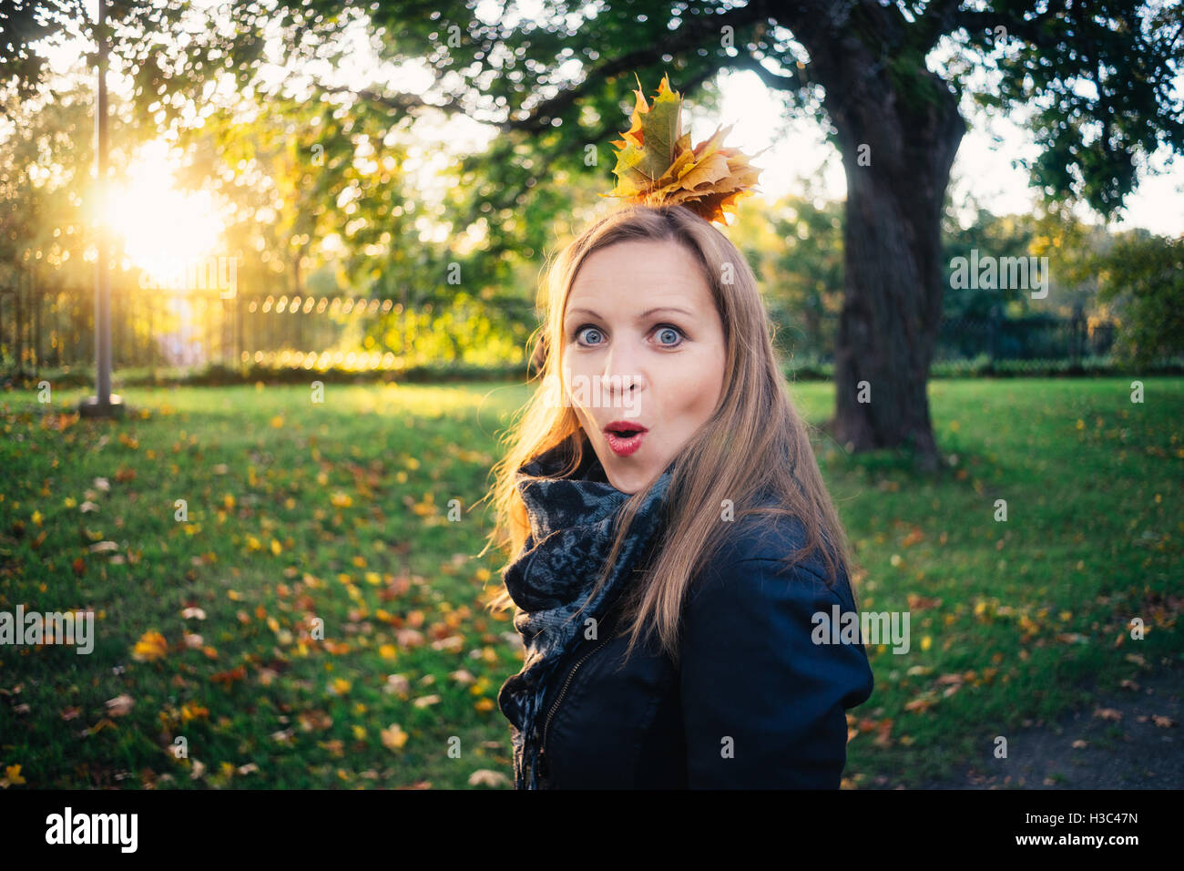 Emotionale junge Frau mit Haufen Blätter suchen im herbstlichen Park überrascht. Herbst-Saison-Konzept Stockfoto