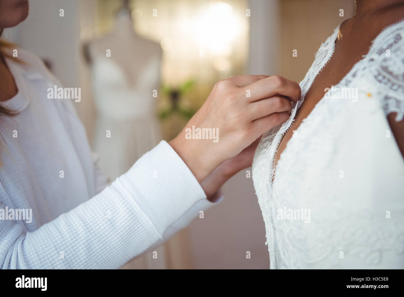 Frau versucht auf Hochzeitskleid mit Hilfe der Mode-designer Stockfoto