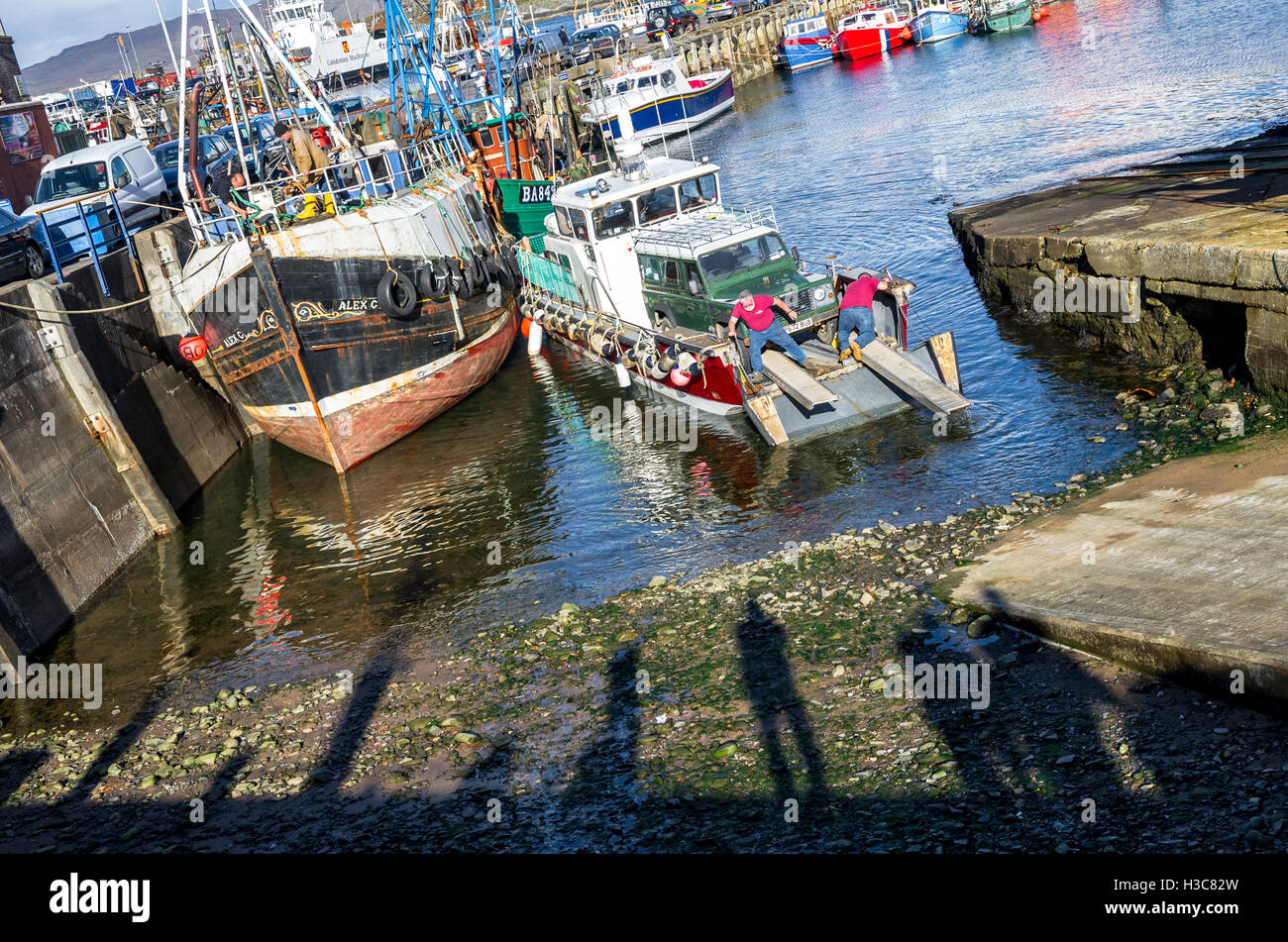 Hafenarbeiter entladen ein Landrover 110 County von einem kleinen Landungsboote am Hafen von Mallaig, Schottisches Hochland. Stockfoto