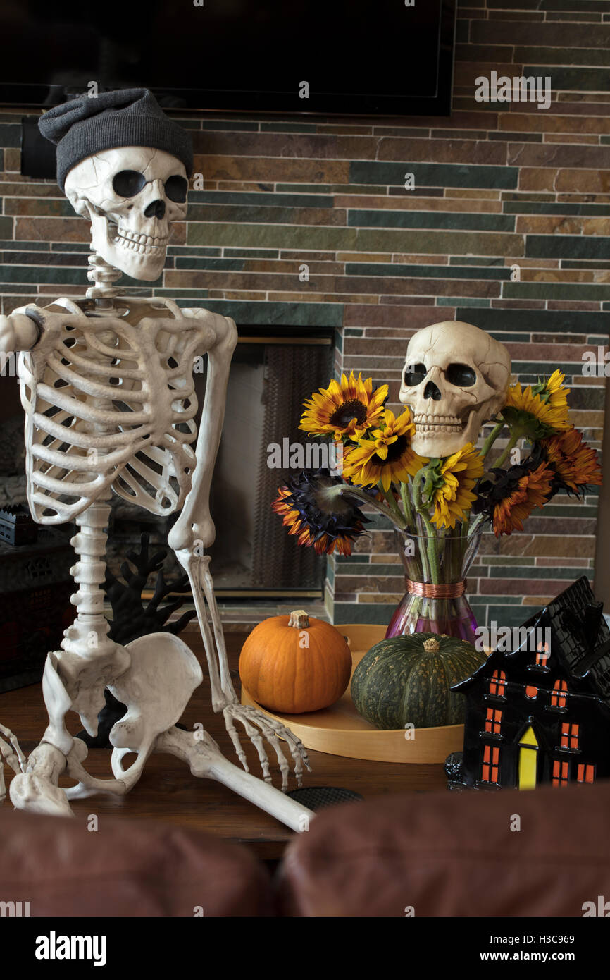 Halloween Skelett sitzt auf dem Sofa und zeigt seinen Urlaub Dekor Stockfoto