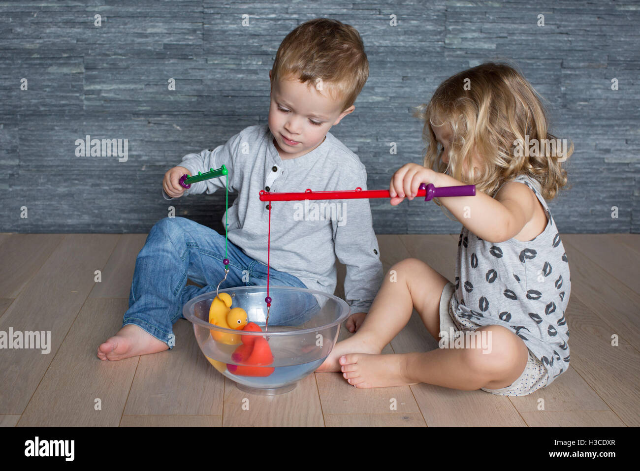 Kinder mit Spielzeug Angelruten, Gummienten schweben in einer großen Schüssel zu fangen Stockfoto