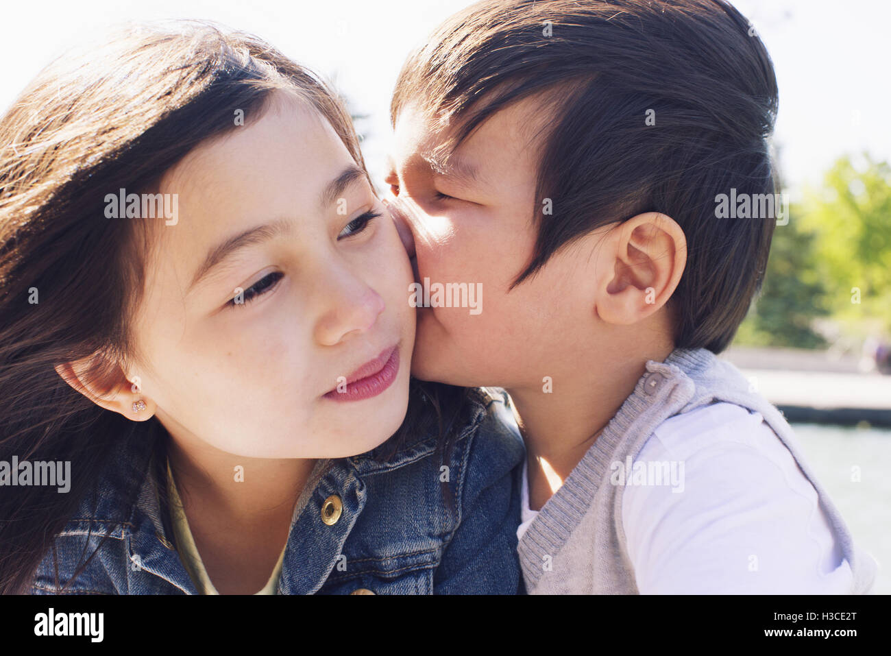 Kleiner Junge seine Schwester Wange küssen Stockfoto