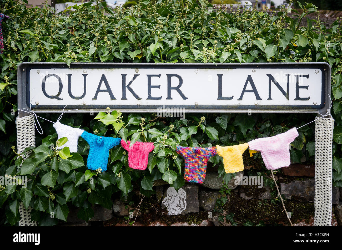 Dorf-Straßenschild QUAKER LANE mit gestrickten Artikeln feiert ein lokales Ereignis in Cumbria Stockfoto