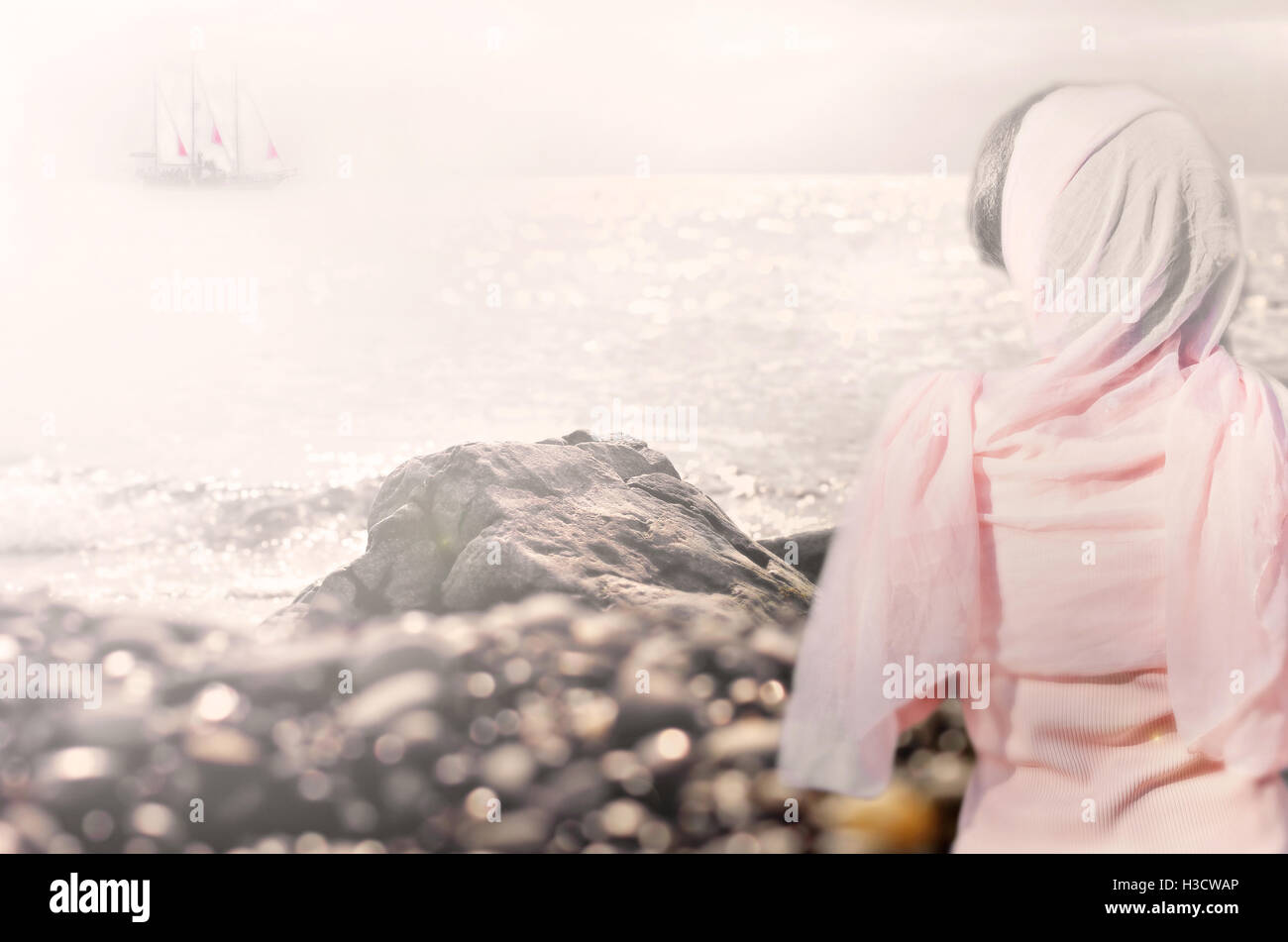 Schiff mit scharlachroten Segel am Horizont und Mädchen in rosa Schal von hinten Stockfoto